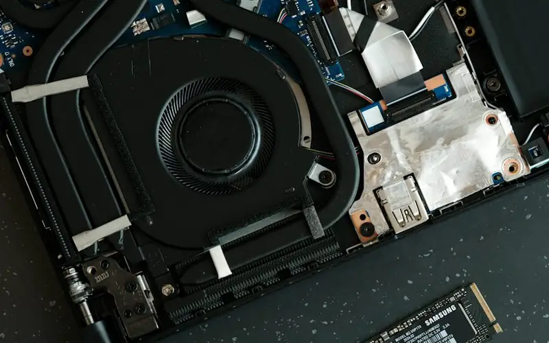 A storage drive being lifted out of an opened laptop
